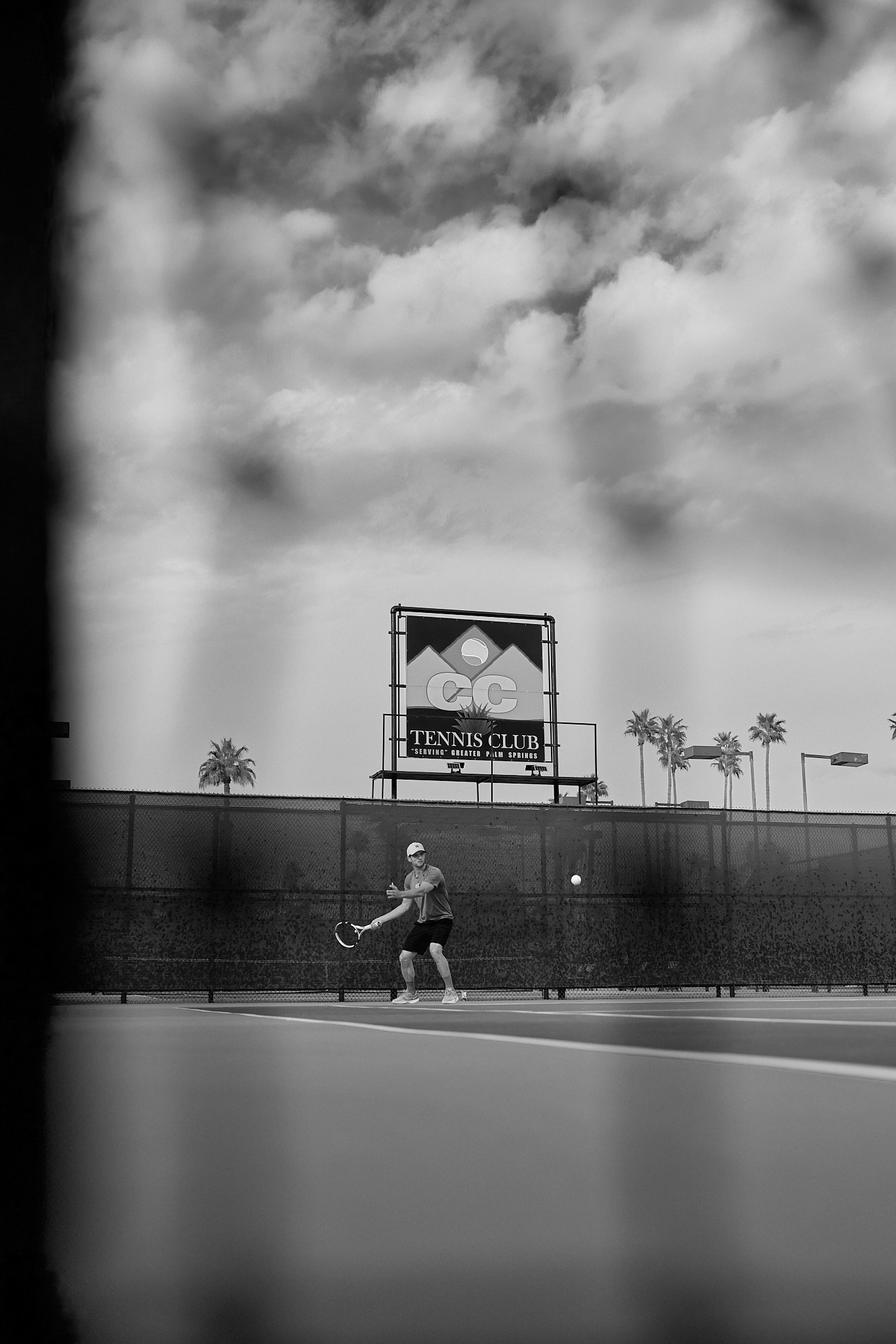 Doubles match with the CC Tennis Club sign and mountains behind